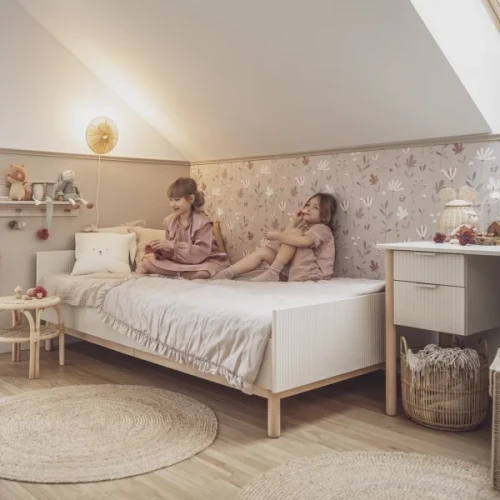 Dziewczynka siedząca na białym łóżku 90×200 cm w jasnym pokoju dziecięcym