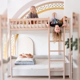 Dziecko na górnym poziomie łóżka piętrowego 90×200 z drabinką, w jasnym pokoju