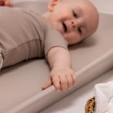 Uśmiechnięte niemowlę na macie do przewijania cappuccino