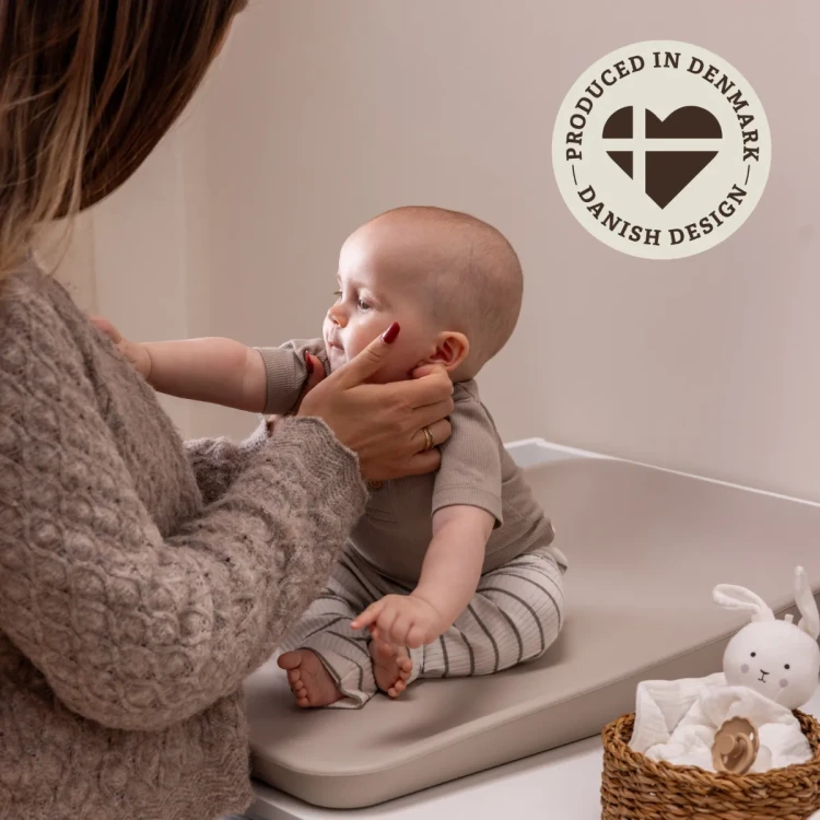 Mama przewijająca dziecko na macie w kolorze cappuccino
